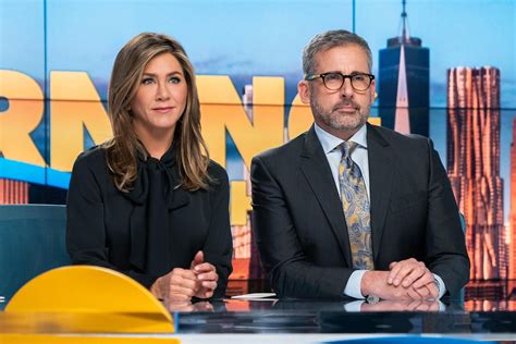 two people sitting at a table in front of a news set