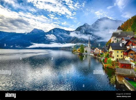 Foggy autumnal sunrise at famous Hallstatt lakeside town reflecting in ...