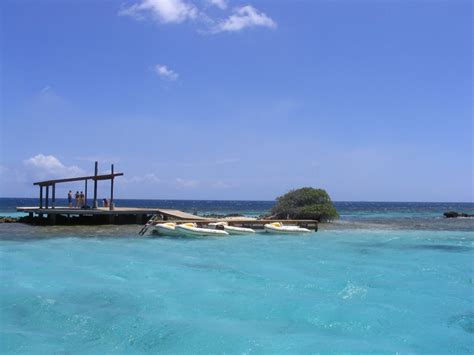 two people standing on a dock in the middle of clear blue water near an ...