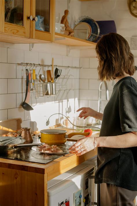 Woman in Gray Long Sleeve Shirt Standing in Front of Kitchen Sink ...