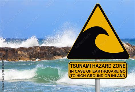 Tsunami warning and evacuation sign located on a beach. The sea and blue sky as background Stock ...