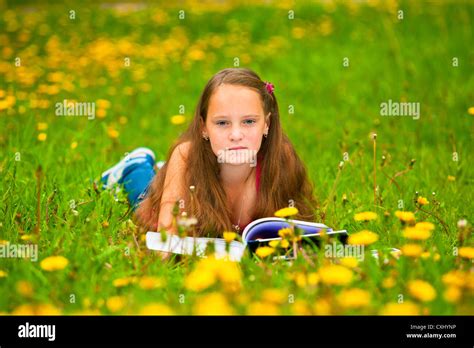 Little girl reading a book while lying in the grass Stock Photo - Alamy