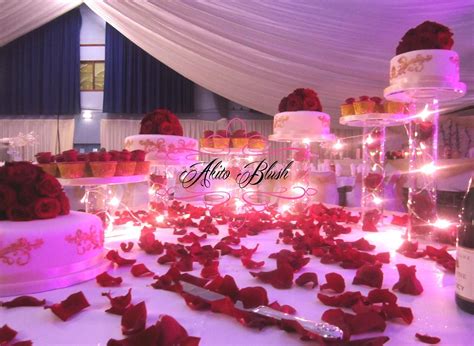7 tier cascading red and gold wedding cake and cupcakes, topped with beautiful grand prix roses ...