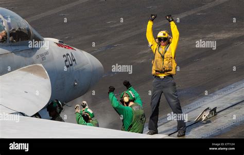 A US Navy sailor on the flight deck crew directs a F/A-18F Super Hornet fighter aircraft during ...