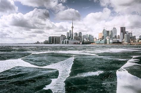 the city skyline is reflected in the ice on the water's surface, while ...