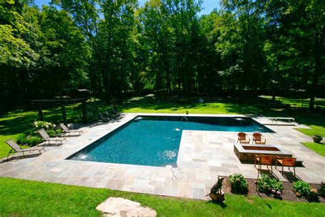 L-Shaped in-ground gunite pool complete with diving board, corner fountains, and sports inserts ...