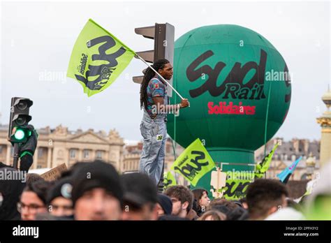 Paris, France 16th Mar, 2023. A protester seen hanging from a traffic light while holding a flag ...