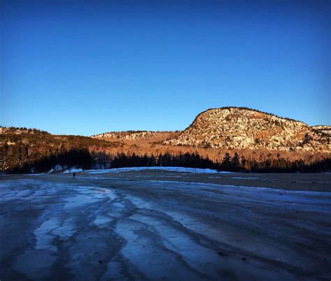 Sunrise light reflects off the Beehive-- seen from Sand Beach in Acadia National Park. Photo ...