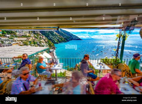 Driving by a cliffside restaurant with tourists dining as they overlook the beautiful Amalfi ...