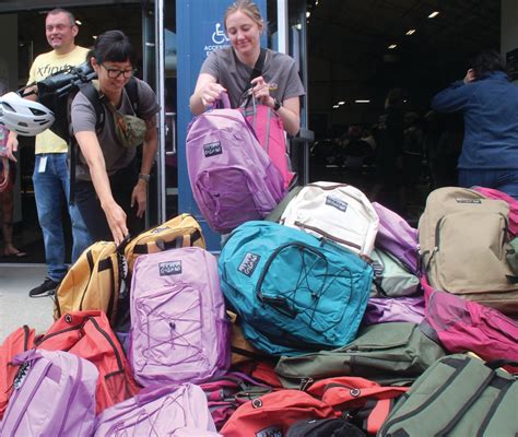 Volunteers fill a mountain of backpacks during Stuff the Bus event