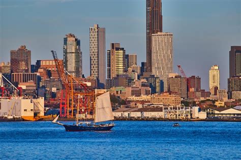 Premium Photo | Skyline of new york city behind ship sailing in bay during golden hour