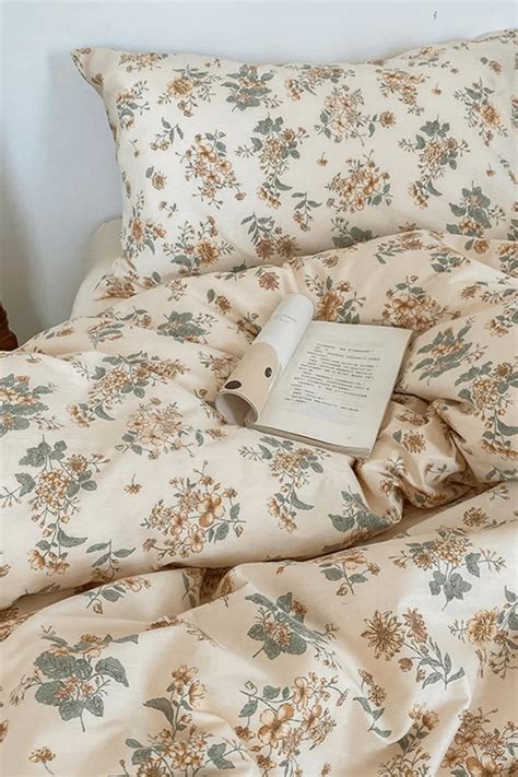 a book is laying on top of a bed with floral comforter and pillows in ...