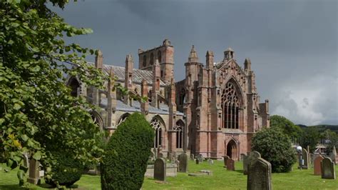 MELROSE, UK - 05 AUGUST 2017: Tourists explore the ruins of Melrose Abbey in this Scottish ...