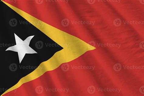 Timor Leste flag with big folds waving close up under the studio light indoors. The official ...