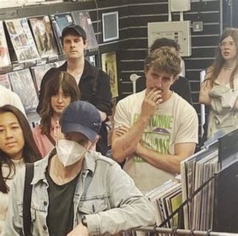 a group of people standing around in a store with masks on their faces and looking at records