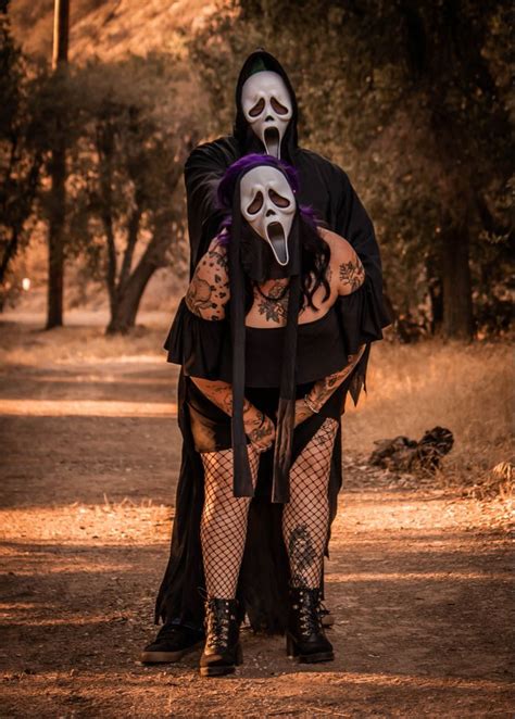 a man dressed in black and white makeup holding a woman with her arms ...