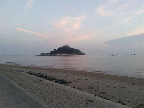 an island in the distance is seen at sunset on a beach with people walking along it