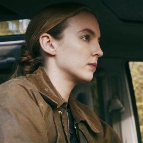 a woman sitting in the back seat of a car wearing a brown jacket and tie