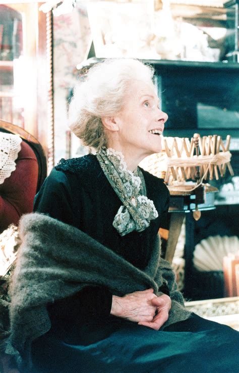 an older woman sitting in a chair with a fur stole around her neck and looking off into the distance