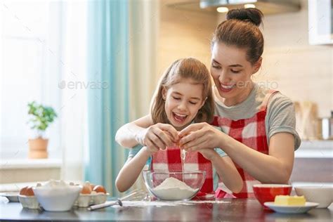 mother and daughter mixing ingredients together in the kitchen - stock photo - images