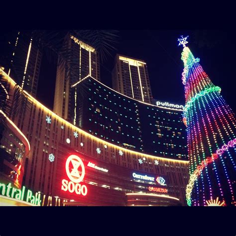 the christmas tree is lit up at night in front of some tall buildings ...