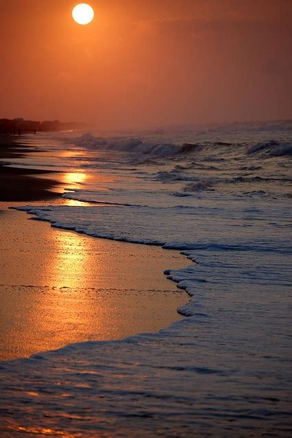 the sun is setting over the water at the beach