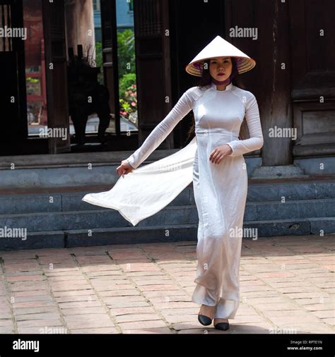 A young Vietnamese woman wearing the traditional dress Ao Dai and the conical hat Non La ...