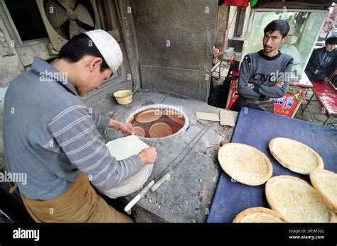 An Uyghur man baking the Naan bread in a tandoor oven in the old city of Kashgar, Xinjiang ...