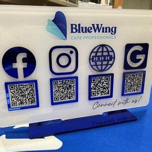 a blue wing sign with qr code and social icons on the front, sitting on a table