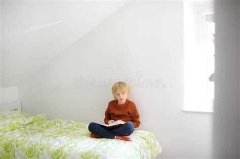 Smart Preteen Boy Sitting on Bed and Enthusiastically Reading ...