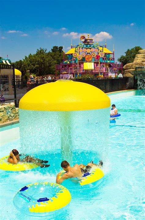 people are swimming in the pool at an amusement park with water slides and splash jets