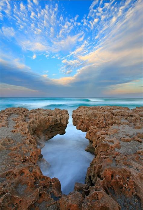 an ocean view with rocks and water in the foreground, under a cloudy ...