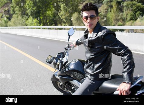 Young Chinese man riding motorcycle Stock Photo - Alamy