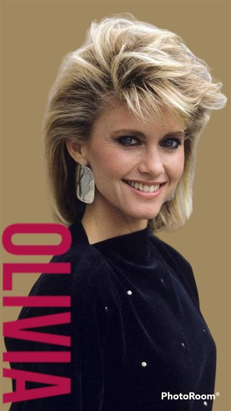 a woman with blonde hair and earrings smiling at the camera in front of ...