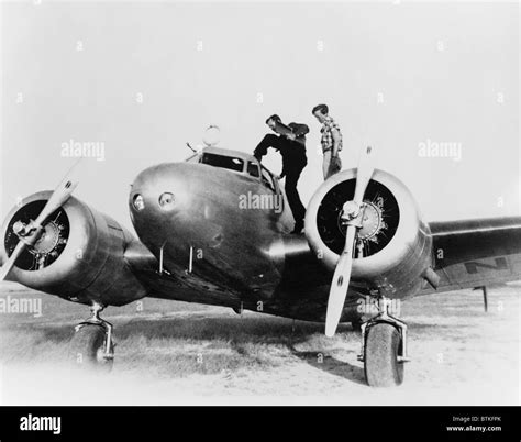 Amelia Earhart stanind on the wing of her Lockheed L-10E Electra airplane. At right is Fred ...