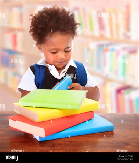 Little clever preschooler in the library, reading books, cute African boy preparing to go to ...