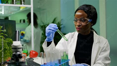 African botanist researcher checking test tubes with dna test liquid ...