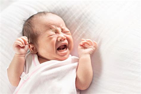 Pequeño bebé lindo recién nacido llorando acostado en la cama. | Foto ...