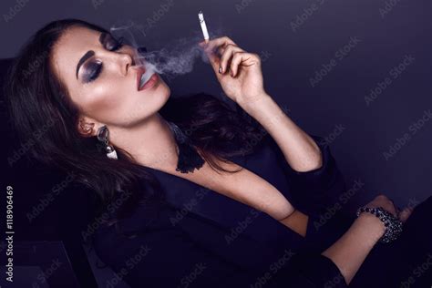 Elegant hot brunette woman smoking a cigarette Stock Photo | Adobe Stock