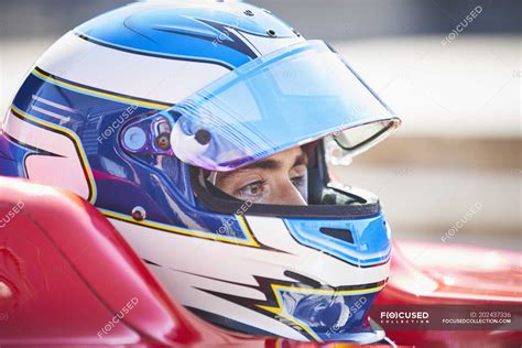 Close up formula one race car driver in helmet looking away ...