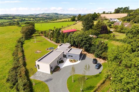 Birds eye aerial view of flat roofs of passive house with landscaped driveway and countryside in ...