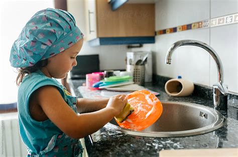 "Little Girl Washing Dishes" by Stocksy Contributor "Marco Govel" - Stocksy