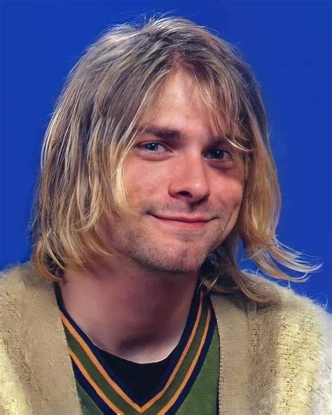 a man with long blonde hair wearing a cardigan sweater and smiling at ...