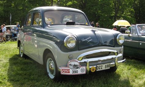 an old car is parked in the grass at a car show with people looking on