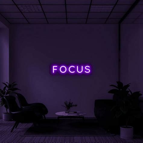 a purple neon sign that reads focus in front of a living room with two chairs and a coffee table