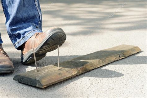 Worker steps on nail — Stock Photo © belchonock #76410619