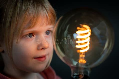 Young Child Looks Focused To a Huge Filament Light Bulb. Symbol for a Happy Child Discovering ...