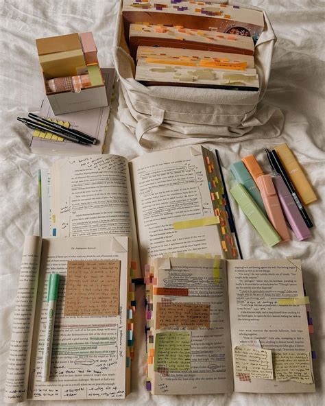 an open book sitting on top of a bed next to some pens and paper clips