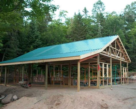 a large wooden building sitting on top of a dirt field next to trees in ...