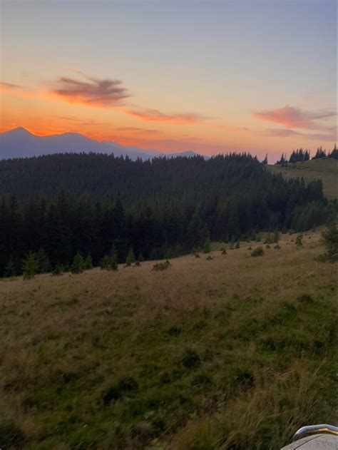 the sun is setting over a field with mountains in the distance and ...